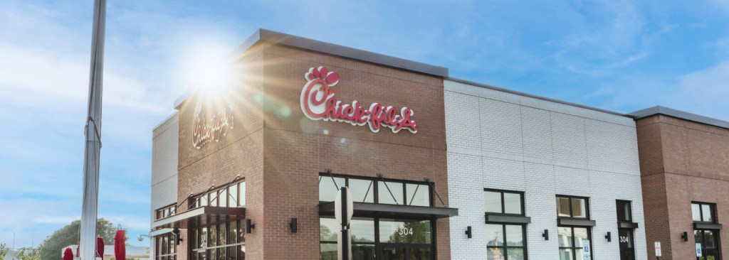 Exterior of a Chick-fil-A restaurant with sunshine and a visible logo.