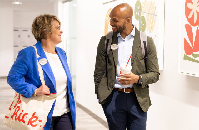 Two co-workers conversing while walking down the hall