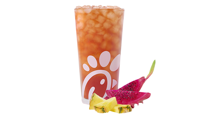 A glass of a Pineapple Dragonfruit Iced Tea by slices of pineapple and dragon fruit.