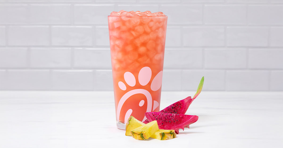 A glass of a Pineapple Dragonfruit Sunjoy® by slices of pineapple and dragon fruit.