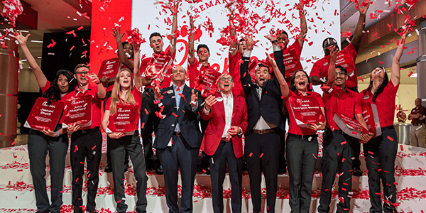 Group of Chick-fil-A Team Members celebrating on stage with confetti falling around them.