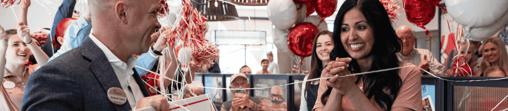 Chick-fil-A Team Member holding a large check and surrounded by other people and balloons