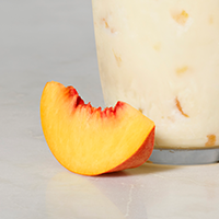 A peach slide sitting on a table next to a glass of Peach Milkshake