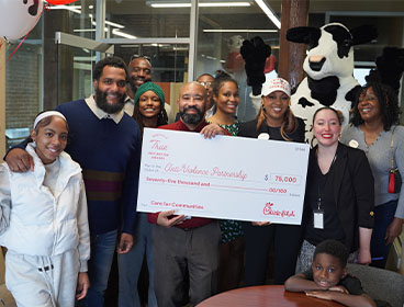 People from the Anti-Violence Partnership standing together smiling and holding a large check