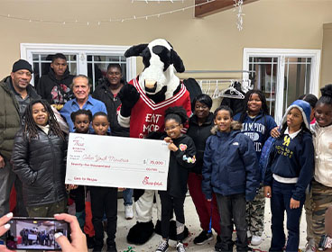 People from the Aslan Youth Ministries standing together with a Chick-fil-A Cow and holding a large check