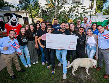 People from the Happy Sonship organization standing together smiling with a Chick-fil-A Cow and holding a large check