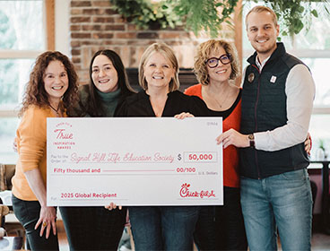 People from the Signal Hill Life Education Society organization standing together smiling and holding a large check