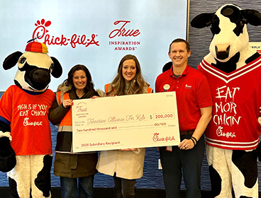 People from Tennessee Alliance for Kids standing together with a Chick-fil-A Cow, holding a large check and smiling