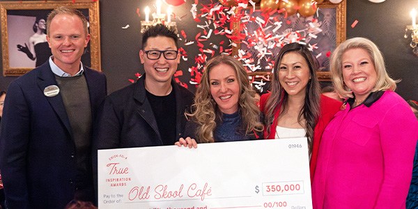 Old Skool Cafe and Chick-fil-A team members celebrating with an over-sized check.