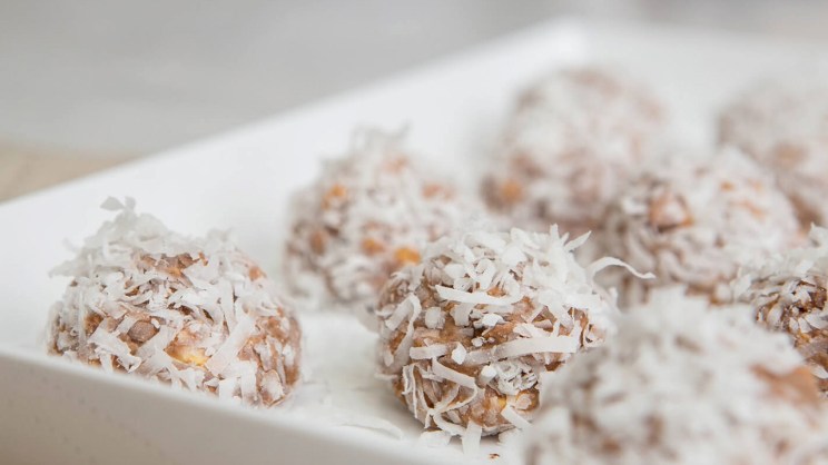 Coconut-covered dessert bites on a white tray.
