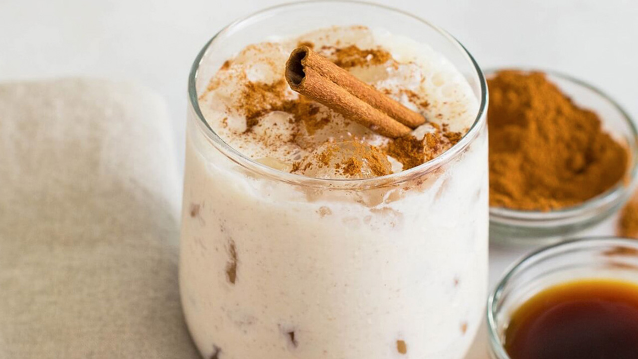 Glass of iced Milkshake Coquito topped with cinnamon.