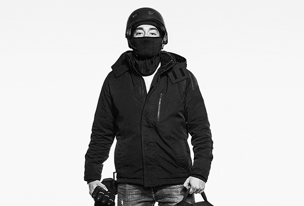 Black-and-white GIF of a smiling food delivery worker riding a bicycle, wearing a winter coat and delivery backpack.