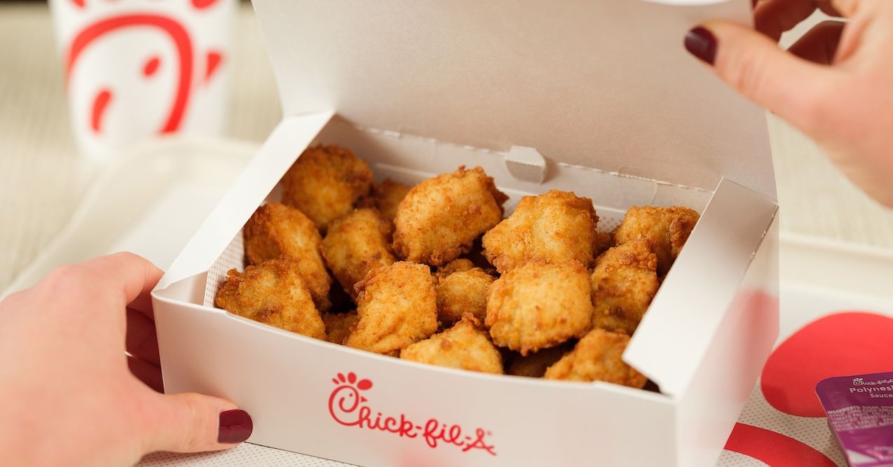 Hands opening a box of Chick-fil-A nuggets