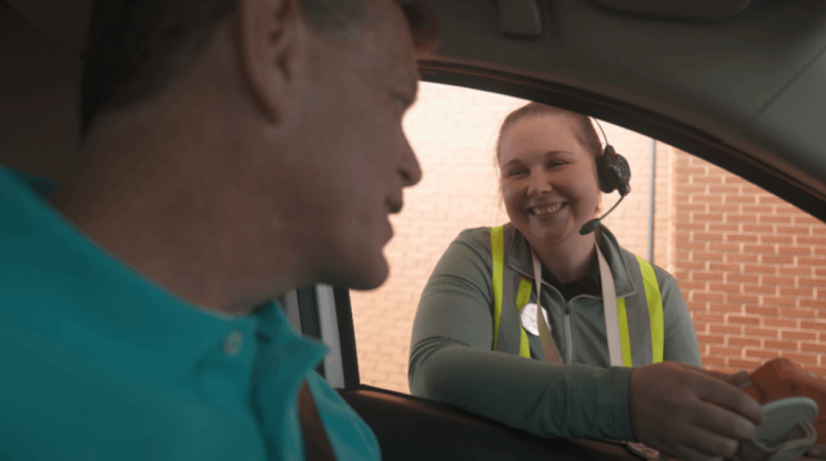 Chick-fil-A employee talking to a customer in a car at the drive-thru.