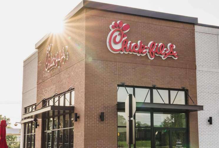 Exterior of a Chick-fil-A restaurant with sunshine and a visible logo.