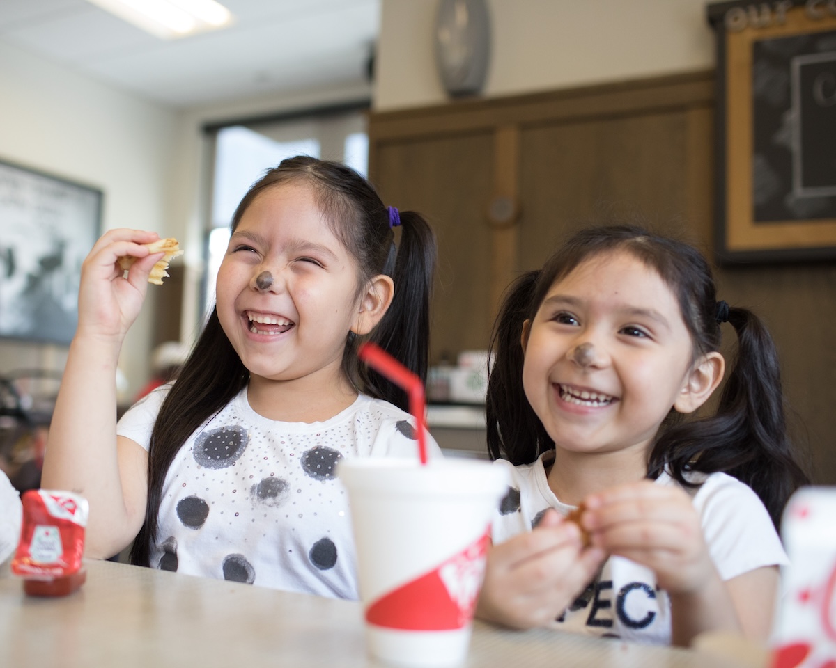 Two young girls dressed in cow costumes inside a Chick-fil-A restaurant.