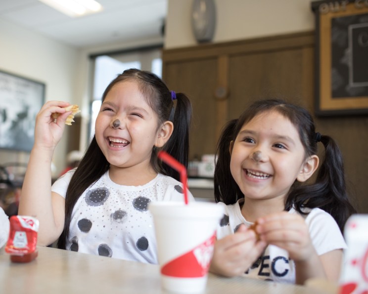 Two young girls dressed in cow costumes inside a Chick-fil-A restaurant.