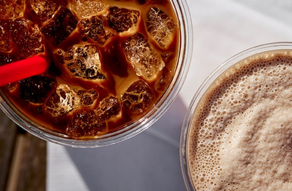 Overhead view of iced coffee with a red straw and a frothy blended coffee drink in clear cups.