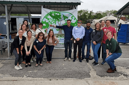 A group of people posing in front of a banner with a tree design.