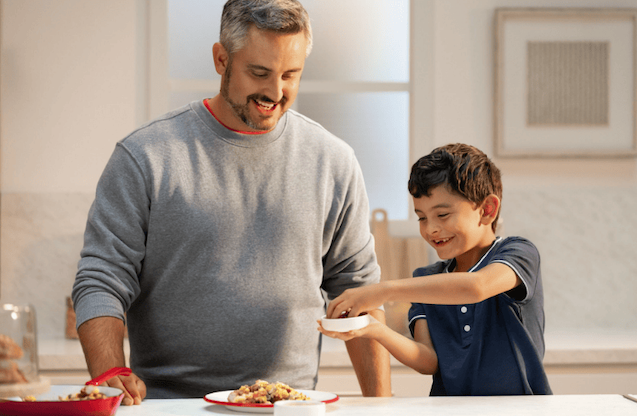 A father and his young son cook together.