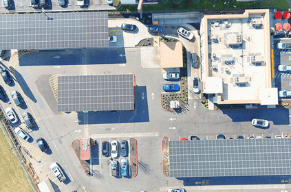 Aerial view of a parking lot with solar panel structures and a building.