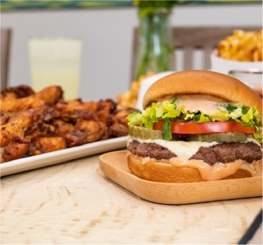 A burger with toppings, wings and waffle fries