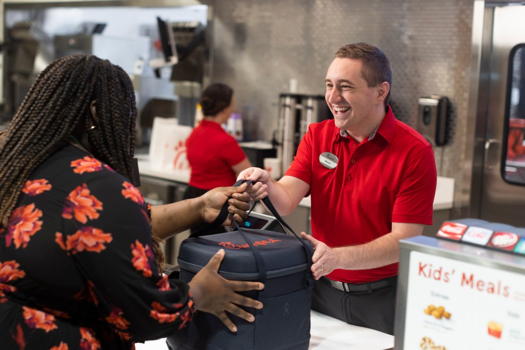 A Chick-fil-A team members hands an insulated bag to a community member.