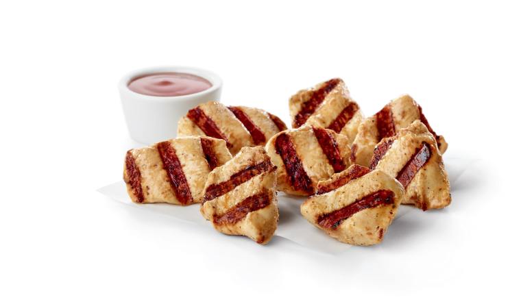 Bite-sized pieces of grilled boneless breast of chicken, served with a side of sauce.
