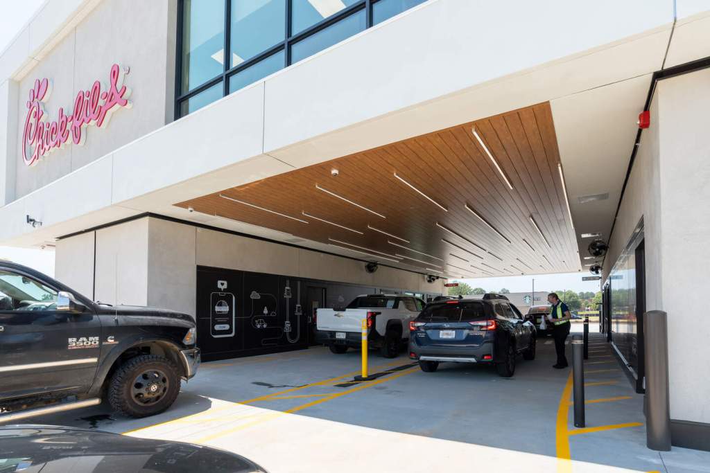 Cars in Chick-fil-A drive-thru under covered lanes with employee taking orders.