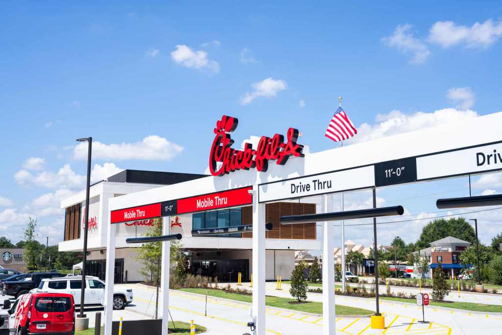 Chick-fil-A drive-thru lanes with “Mobile Thru” and “Drive Thru” signs under American flag.