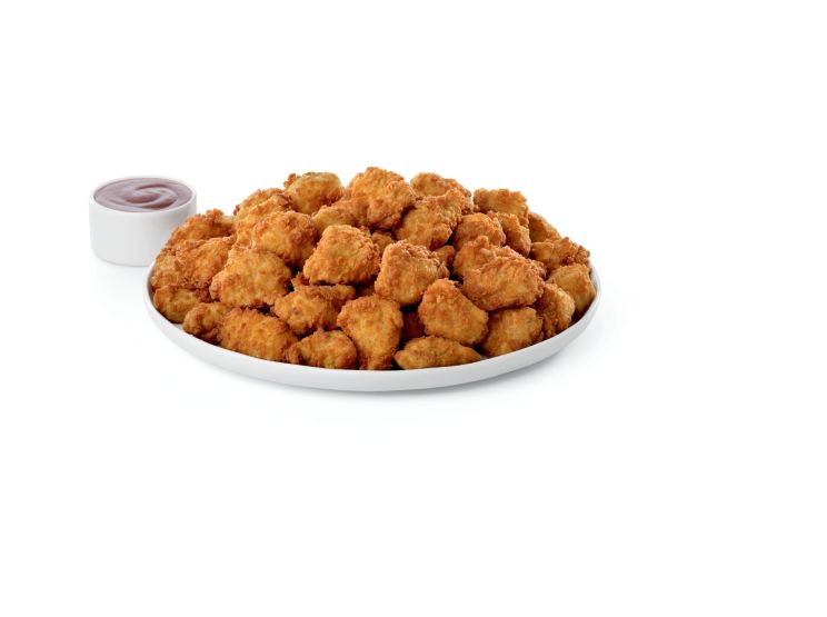 A tray of bite-sized pieces of tender chicken breast served with a sauce.