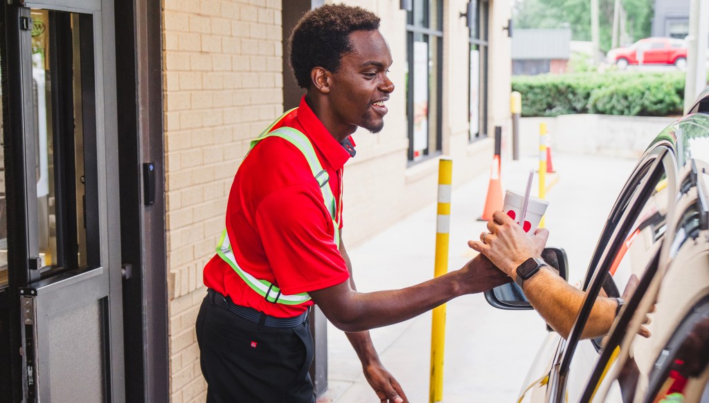 Restaurant Team Member handing a beverage to a customer in the drive-thru