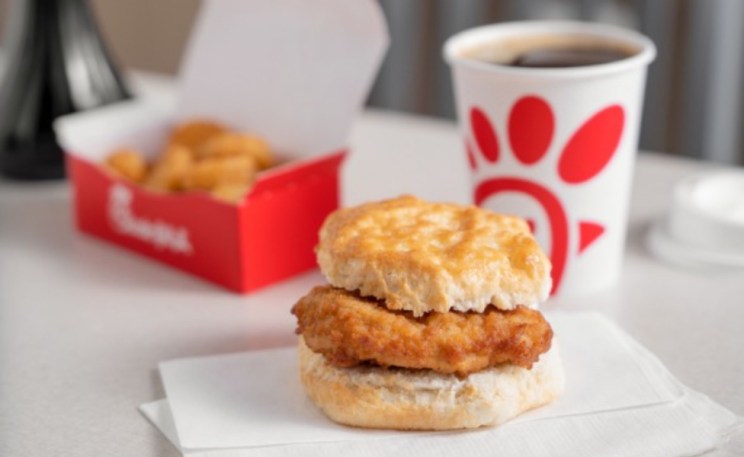 Chick-fil-A® Chicken Biscuit on white napkins with a cup of Coffee and a box of Hash Browns