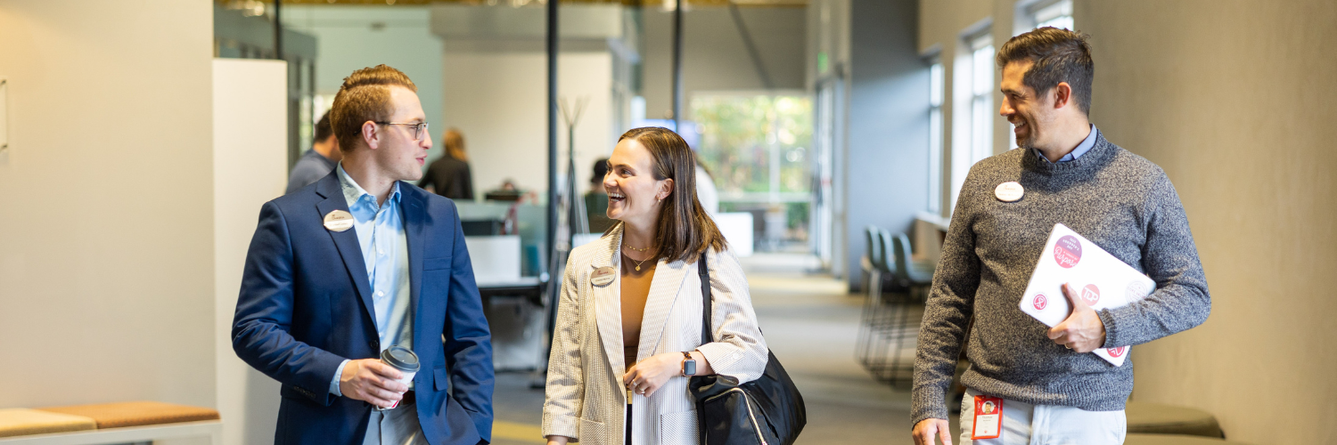 Three people walking and talking inside an office building
