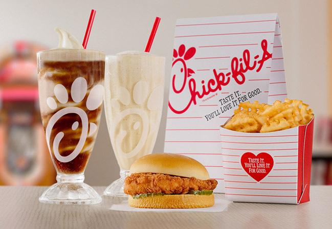 Chick-fil-A® Chicken Sandwich with Waffle Fries, a glass of Frosted Coca-Cola® Soda, a glass of Coca-Cola® Float and a Chick-fil-A bag behind them