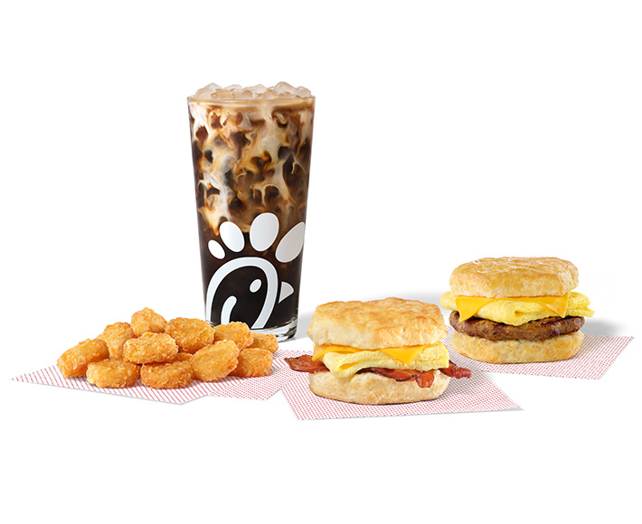 Bacon, Egg & Cheese Biscuit and Sausage, Egg & Cheese Biscuit on parchment paper with Hash Browns on parchment paper and an Iced Coffee