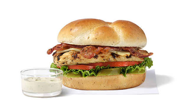 A Jalapeño Ranch Club sandwich with a Grilled Filet on a white napkin next to a small a glass bowl of Jalapeño Ranch Sauce