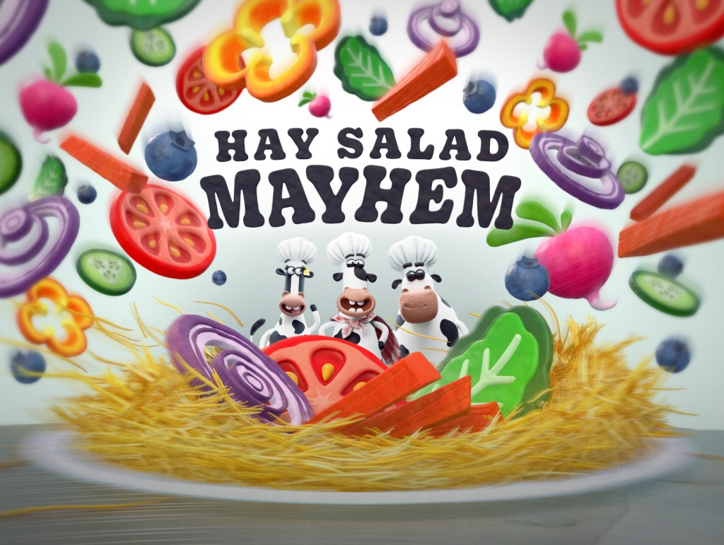 Chick-fil-A Play Cows standing in front of an oversized bowl of hay and salad with salad items in the air around them and the words “Hay Salad Mayhem” above them