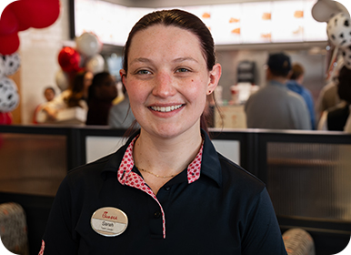 Headshot of Team Member Sarah standing in a Restaurant smiling