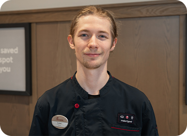 Headshot of Team Member Caleb standing in a Restaurant smiling