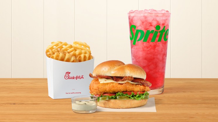 A Jalapeño Ranch Club with the Original Filet and a side of Jalapeño Ranch Sauce with Waffle Fries, and a Strawberry Hibiscus & Sprite® on a table.