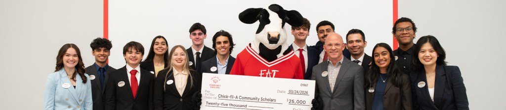 Group of people standing together with a Chick-fil-A Cow holding a large check