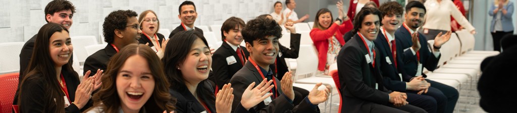 Group of people sitting and standing together on a red couch with a Chick-fil-A Cow and holding a large check