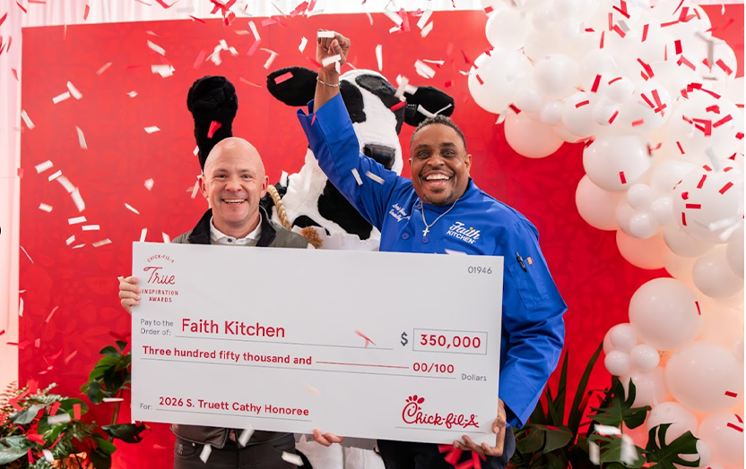 Two people holding a large check with confetti and ballons around them