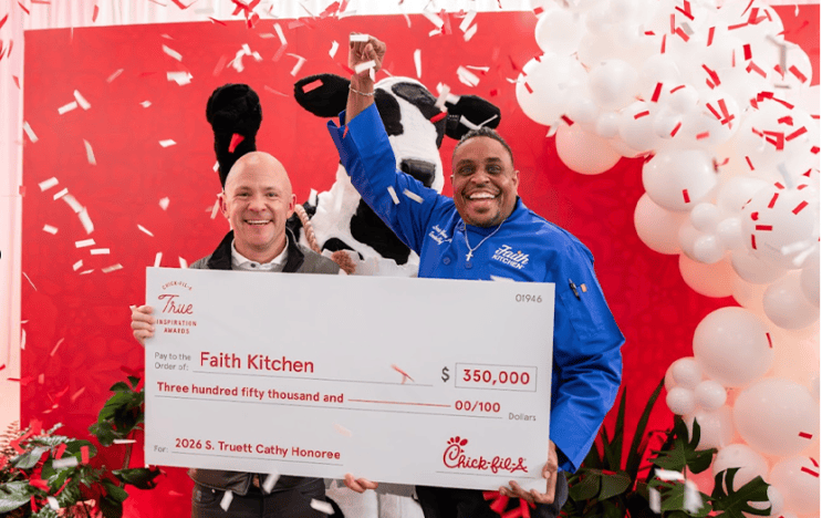 Two people holding a large check with confetti and ballons around them