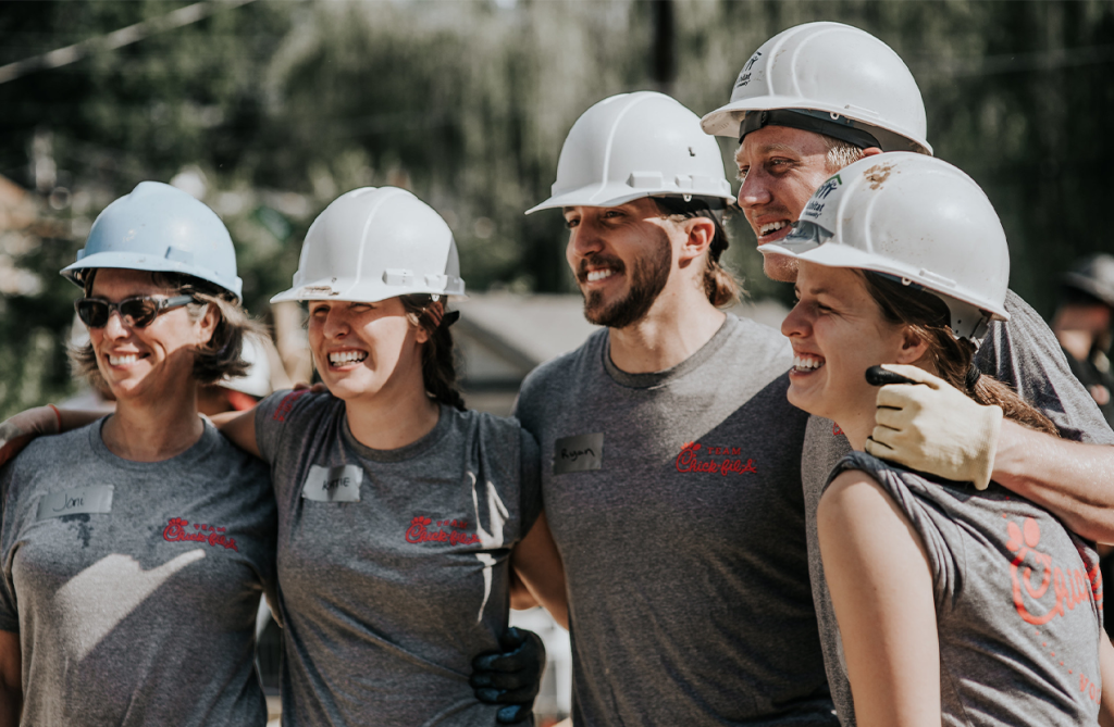Group of five people wearing hard hats and standing together smiling