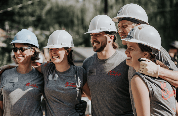 Group of five people wearing hard hats and standing together smiling