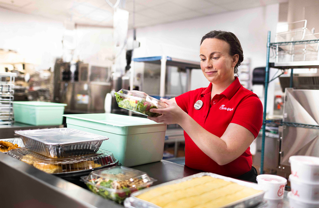 A Team Member placing a salad inside a storage container