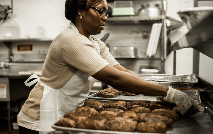 A person placing baked potatoes on a pan
