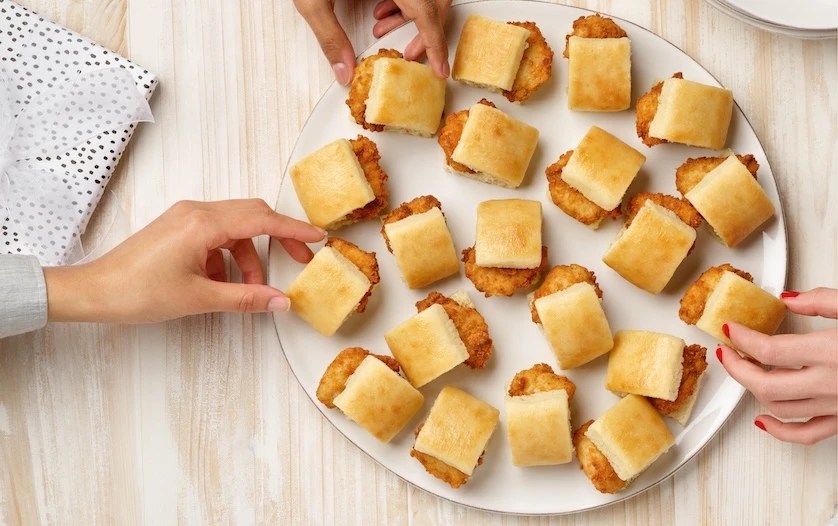 People reaching for Chick-fil-A Chick-n-Minis® on a white platter